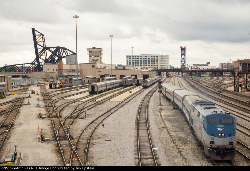 AMTK 33 leads a train by the maintenance facility 